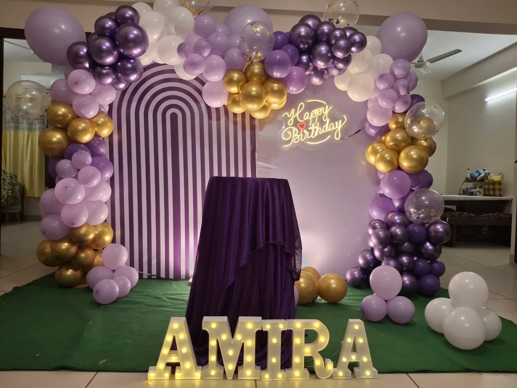 First birthday decoration setup with balloon arch, themed backdrop, cake table decoration, stage setup, and family celebration by Joyful Knots Events